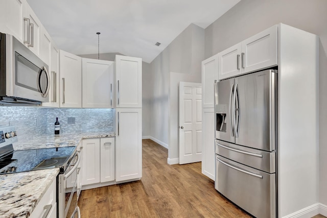 kitchen featuring light stone countertops, white cabinetry, stainless steel appliances, light hardwood / wood-style floors, and decorative backsplash