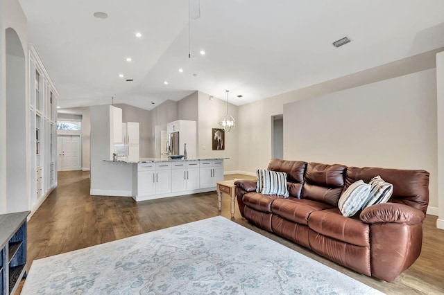 living room with a notable chandelier, vaulted ceiling, and hardwood / wood-style flooring