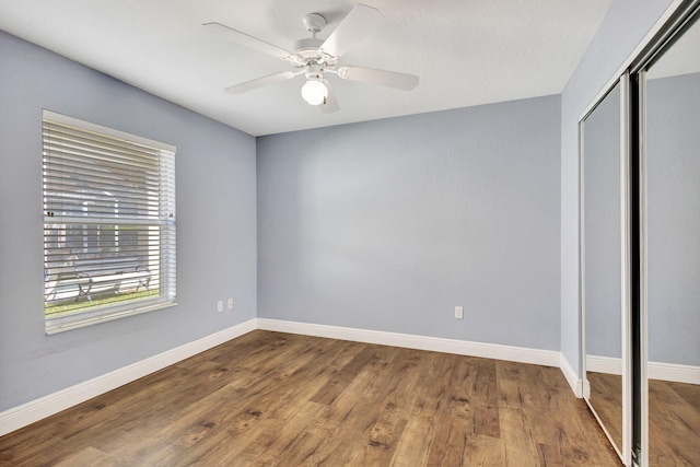 unfurnished bedroom featuring ceiling fan, a closet, and wood-type flooring