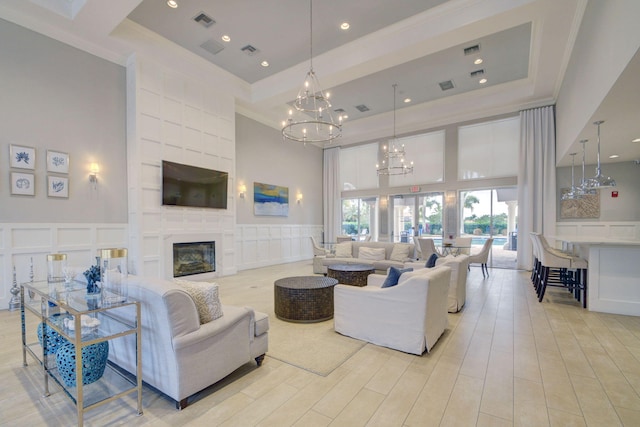 living room with a towering ceiling, a chandelier, and ornamental molding