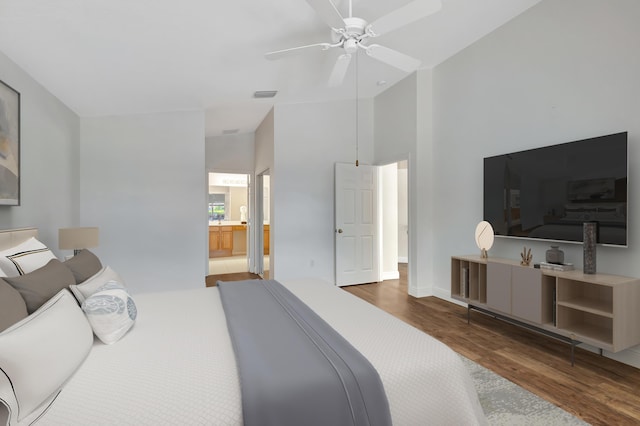 bedroom featuring connected bathroom, vaulted ceiling, ceiling fan, and dark wood-type flooring