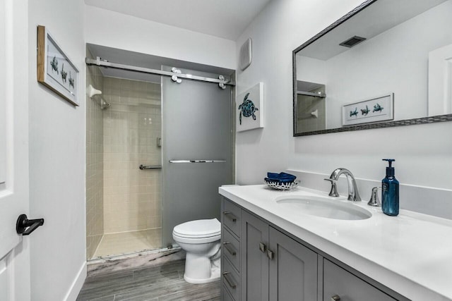 bathroom featuring vanity, toilet, and a shower with shower door