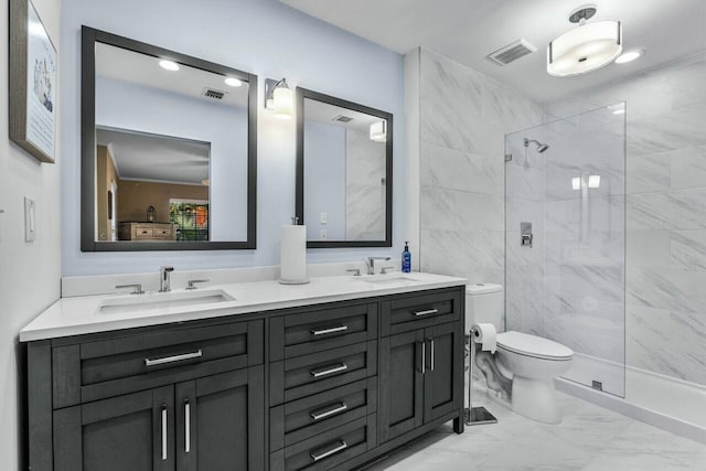 bathroom featuring a tile shower, vanity, and toilet