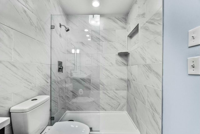 bathroom featuring tiled shower and toilet