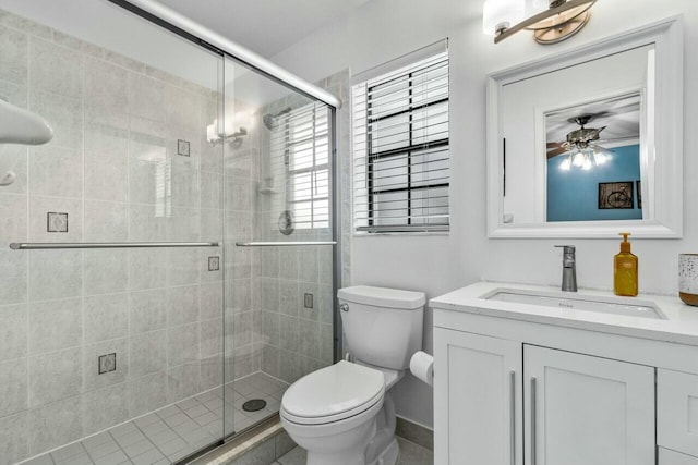 bathroom with vanity, a shower with door, toilet, and ceiling fan