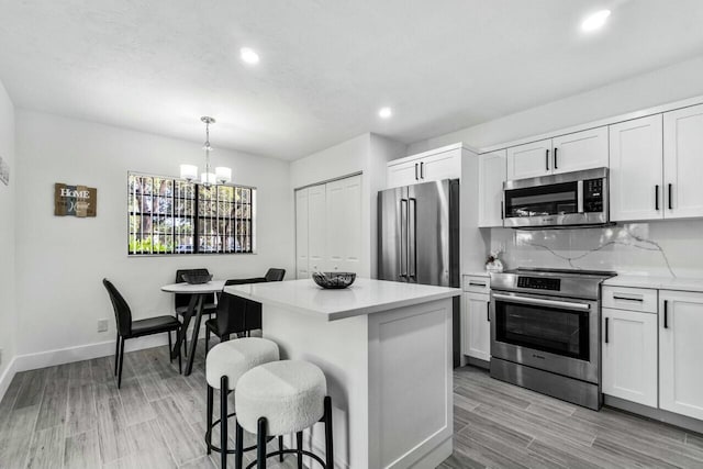 kitchen with white cabinets, decorative light fixtures, a center island, and stainless steel appliances