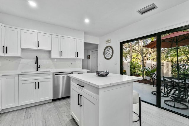 kitchen featuring white cabinetry, dishwasher, a center island, sink, and tasteful backsplash