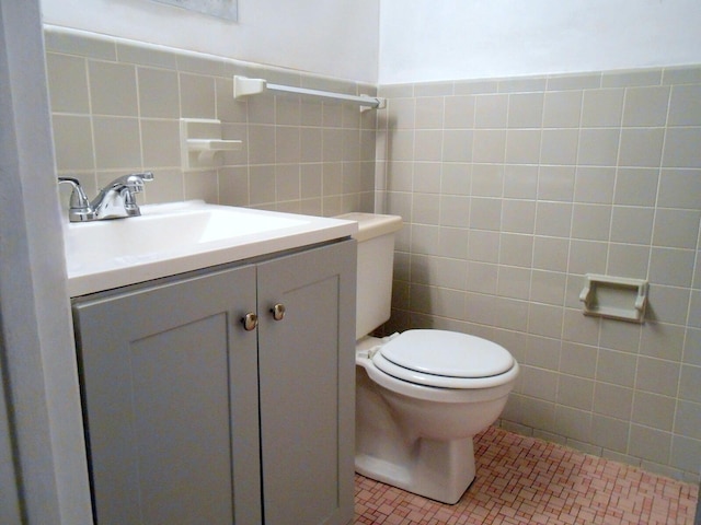 bathroom featuring tile walls, toilet, vanity, and tile patterned flooring