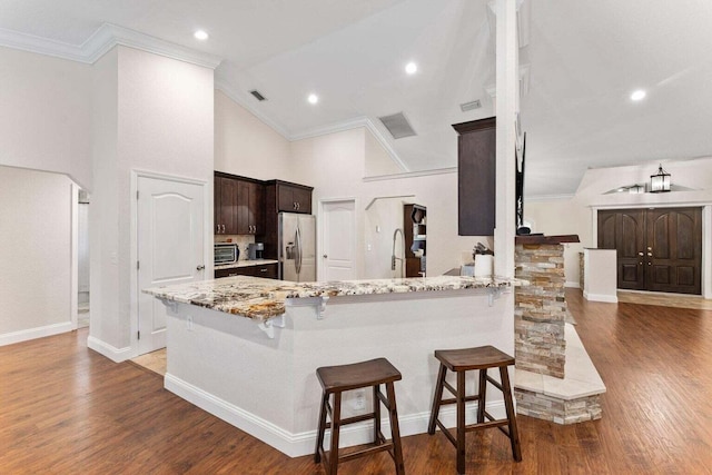 kitchen featuring high vaulted ceiling, crown molding, kitchen peninsula, a kitchen bar, and stainless steel fridge with ice dispenser