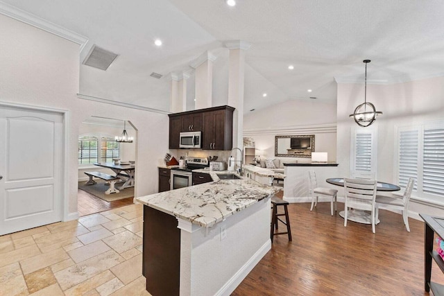 kitchen featuring kitchen peninsula, dark brown cabinets, stainless steel appliances, sink, and pendant lighting