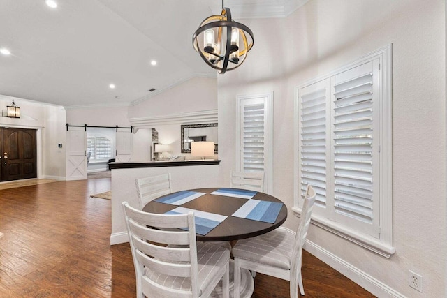 dining space with lofted ceiling, dark wood-type flooring, a barn door, ornamental molding, and a chandelier