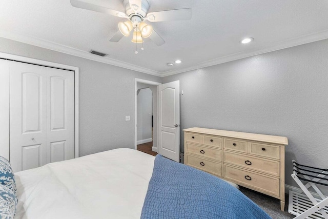 bedroom featuring ceiling fan, dark carpet, crown molding, and a closet