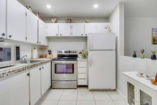 kitchen featuring light tile patterned floors, white appliances, white cabinetry, and sink