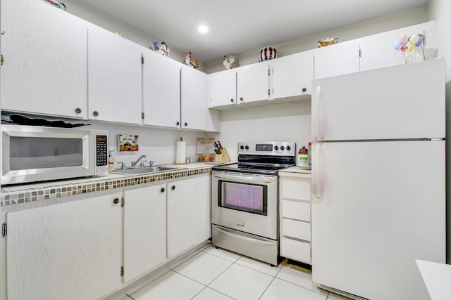 kitchen with light tile patterned floors, white appliances, white cabinetry, and sink