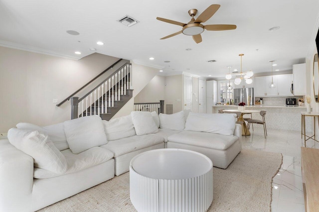 living room featuring ceiling fan with notable chandelier and ornamental molding