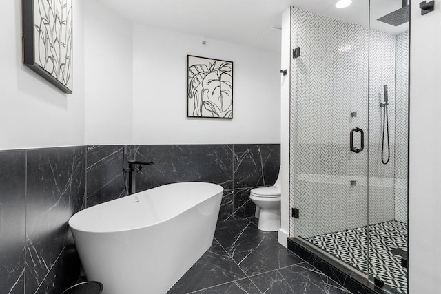 bathroom featuring toilet, tile walls, and independent shower and bath