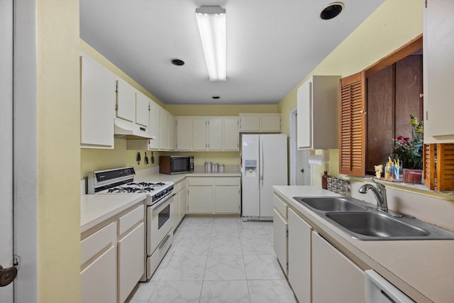 kitchen with sink, white appliances, and white cabinetry