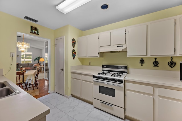 kitchen with white gas stove, an inviting chandelier, white cabinetry, and hanging light fixtures