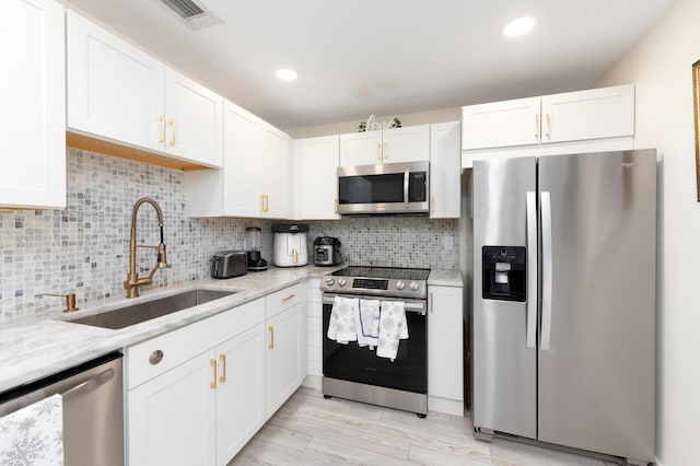 kitchen with white cabinetry, sink, light stone countertops, and appliances with stainless steel finishes