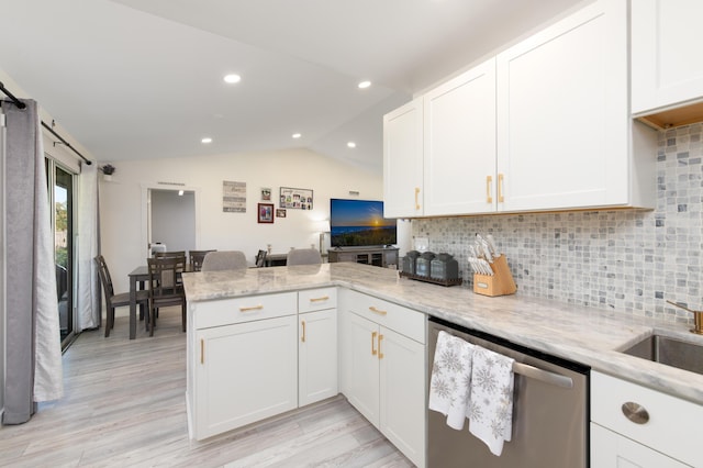 kitchen featuring stainless steel dishwasher, lofted ceiling, light stone counters, and white cabinetry