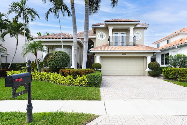 mediterranean / spanish home featuring a balcony, a front lawn, and a garage