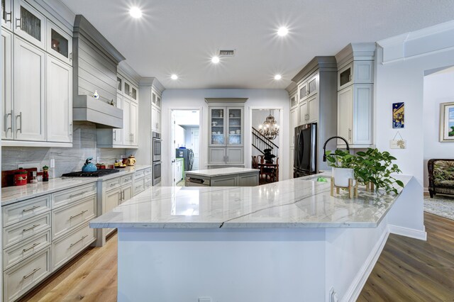 living room with a towering ceiling, hardwood / wood-style floors, an inviting chandelier, and ornamental molding