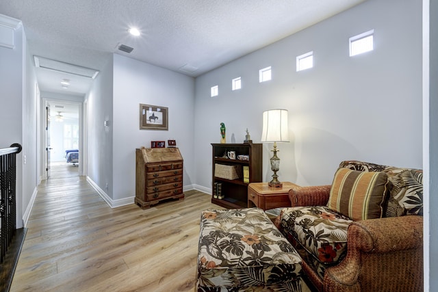 living area with a textured ceiling and light wood-type flooring