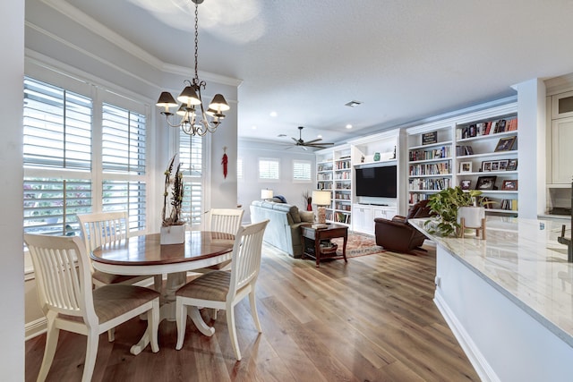 dining area featuring hardwood / wood-style flooring, ceiling fan with notable chandelier, and crown molding