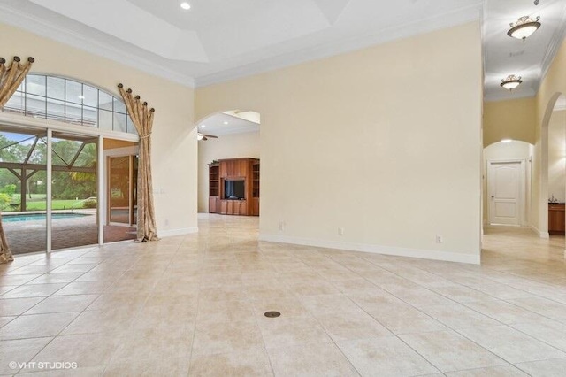 tiled empty room featuring a raised ceiling, crown molding, a towering ceiling, and ceiling fan