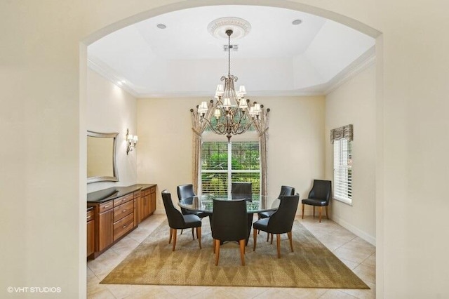 tiled dining area featuring a tray ceiling, crown molding, and a notable chandelier