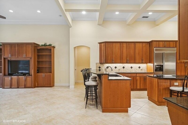 kitchen featuring a breakfast bar area, a center island, beamed ceiling, and stainless steel built in refrigerator