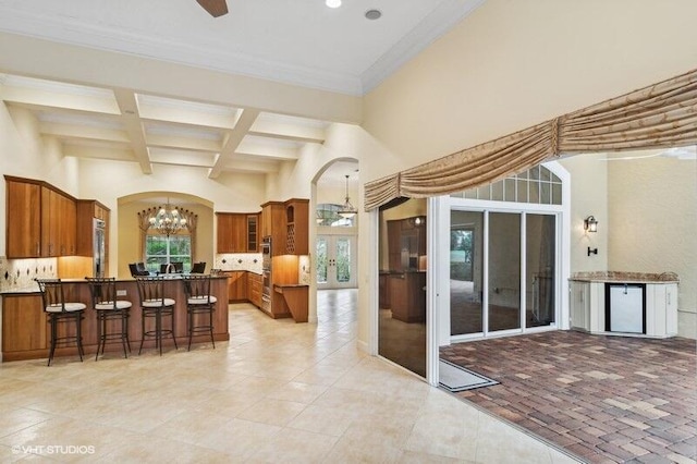 interior space with beamed ceiling, a breakfast bar, kitchen peninsula, and backsplash