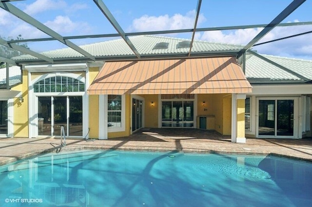 rear view of property with glass enclosure and a patio area