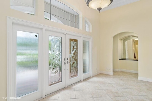 doorway to outside with light tile patterned floors, a towering ceiling, and french doors