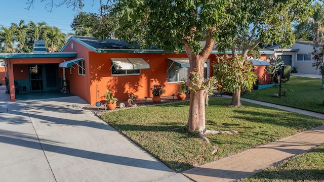 view of front of property featuring a carport, a front yard, concrete driveway, and stucco siding