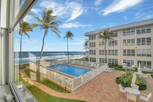 view of swimming pool featuring a view of the beach, a patio area, and a water view