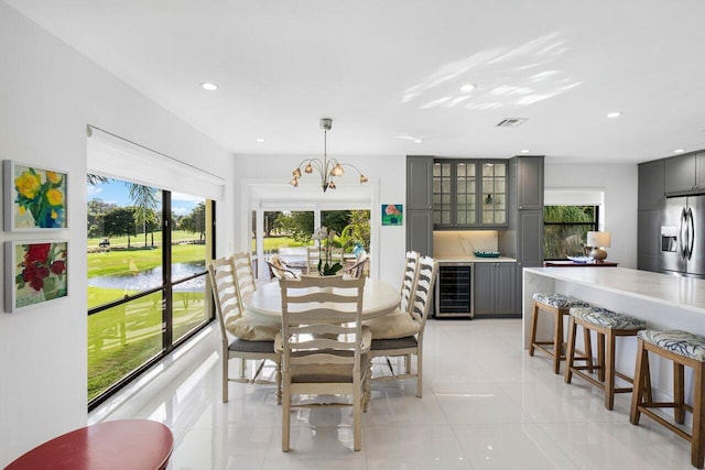 tiled dining area featuring a water view, wine cooler, and a chandelier