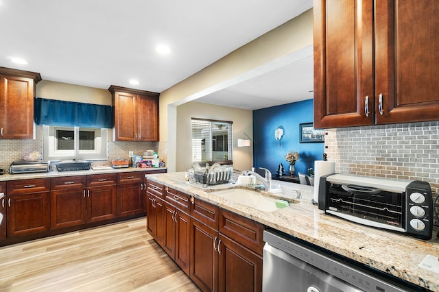 kitchen featuring dishwasher, sink, tasteful backsplash, light stone counters, and light wood-type flooring