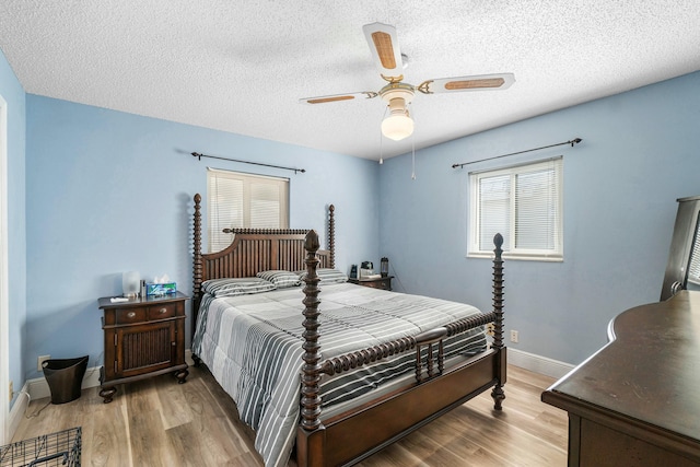 bedroom with ceiling fan, light hardwood / wood-style floors, and a textured ceiling