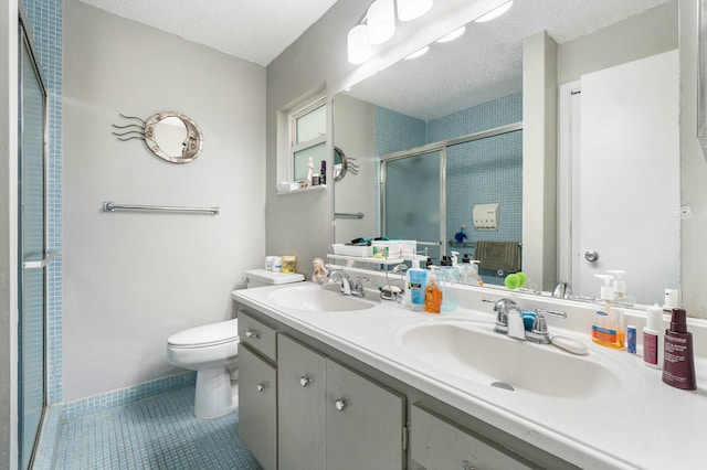 bathroom featuring tile patterned floors, vanity, a textured ceiling, toilet, and a shower with shower door