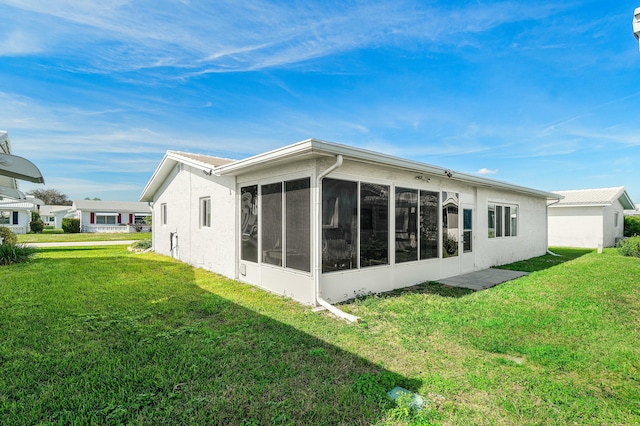 rear view of house featuring a sunroom and a yard