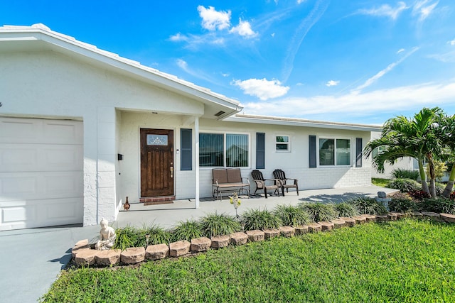 property entrance featuring a yard, covered porch, and a garage