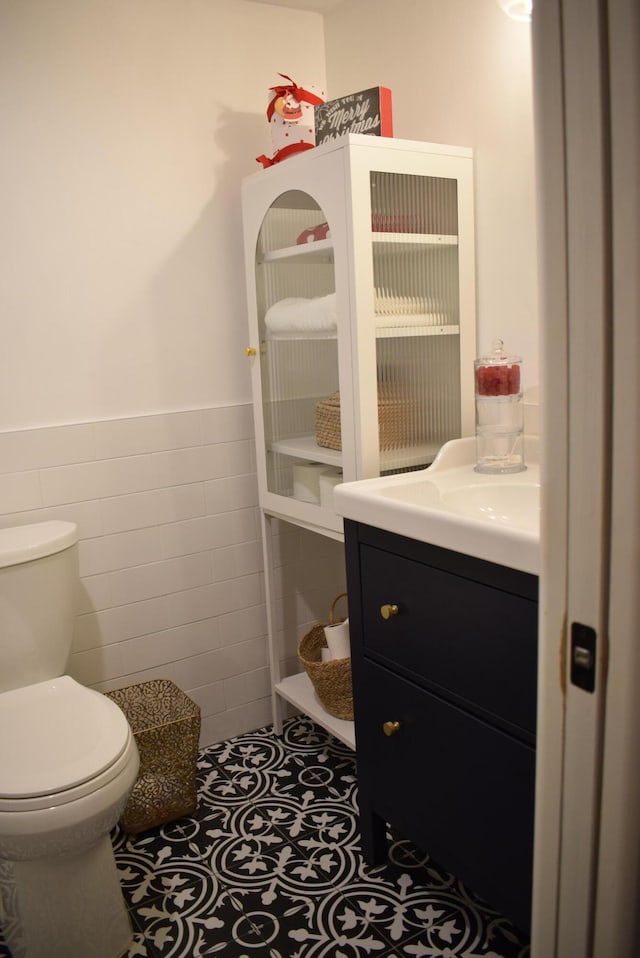 bathroom featuring tile walls, vanity, tile patterned floors, and toilet