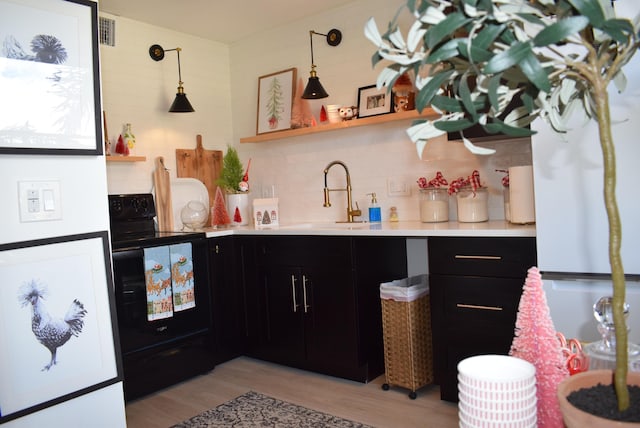 kitchen with pendant lighting, sink, decorative backsplash, light hardwood / wood-style floors, and black / electric stove