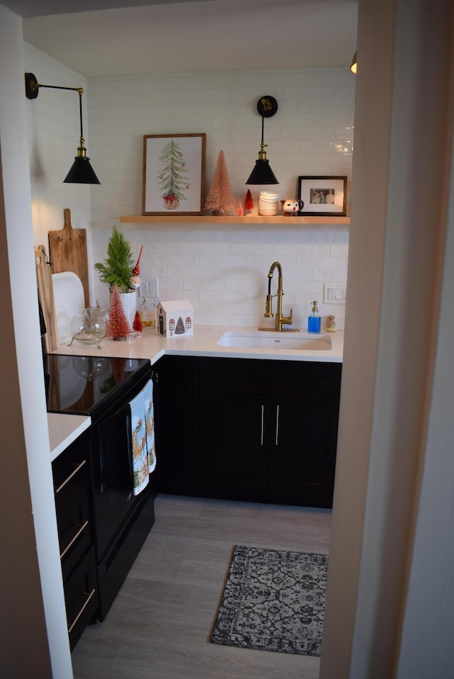 kitchen featuring sink, decorative light fixtures, black range with electric stovetop, hardwood / wood-style floors, and backsplash