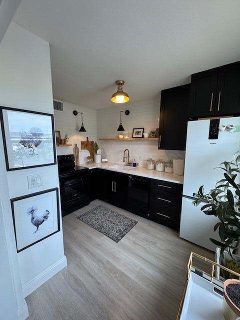 kitchen with sink, light wood-type flooring, electric range, white fridge, and backsplash