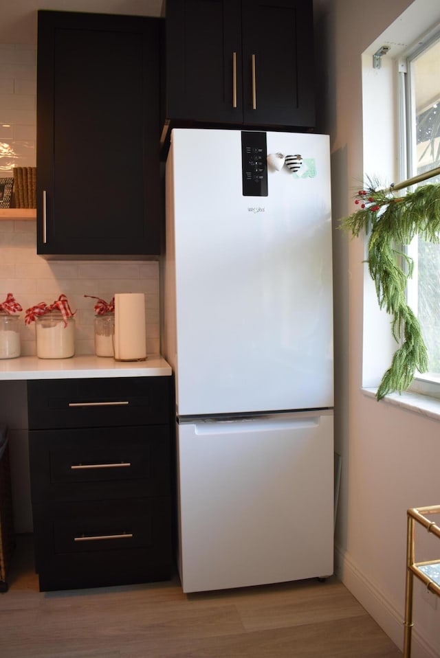 kitchen with tasteful backsplash, light hardwood / wood-style flooring, and white fridge