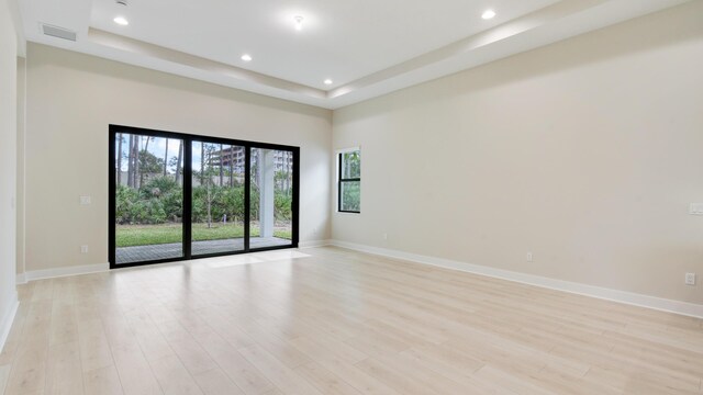 unfurnished room with a raised ceiling and light wood-type flooring