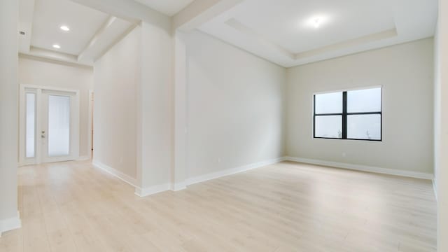 empty room featuring a tray ceiling and light hardwood / wood-style flooring