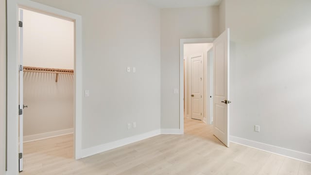 unfurnished bedroom featuring a spacious closet, light wood-type flooring, and a closet